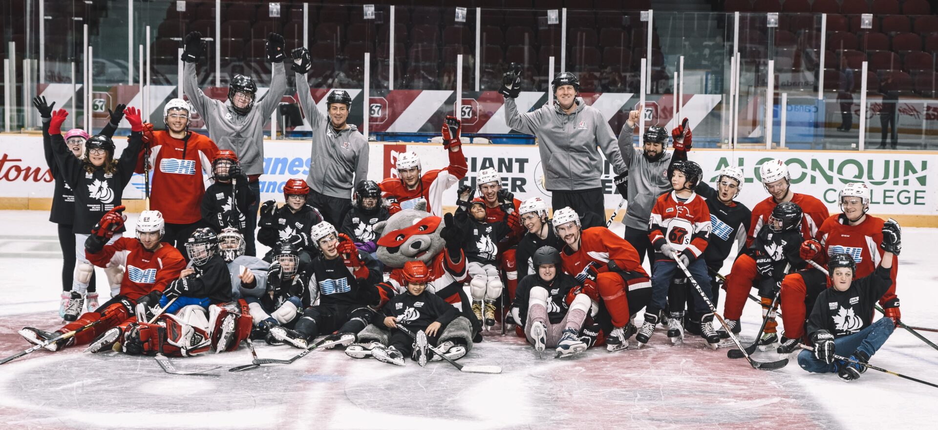 young hockey players posing with 67's players in a group team shot on the ice